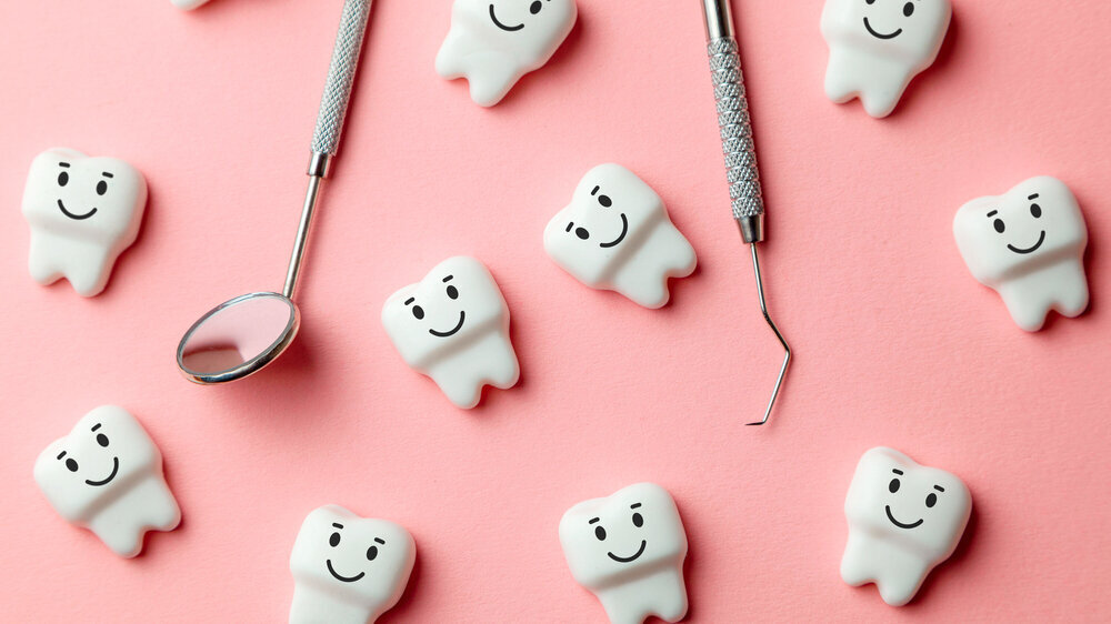 Healthy white teeth are smiling on pink background and dentist tools mirror, hook. Modelle von gesunden weißen Zähne lächeln auf rosafarbenem Hintergrund.