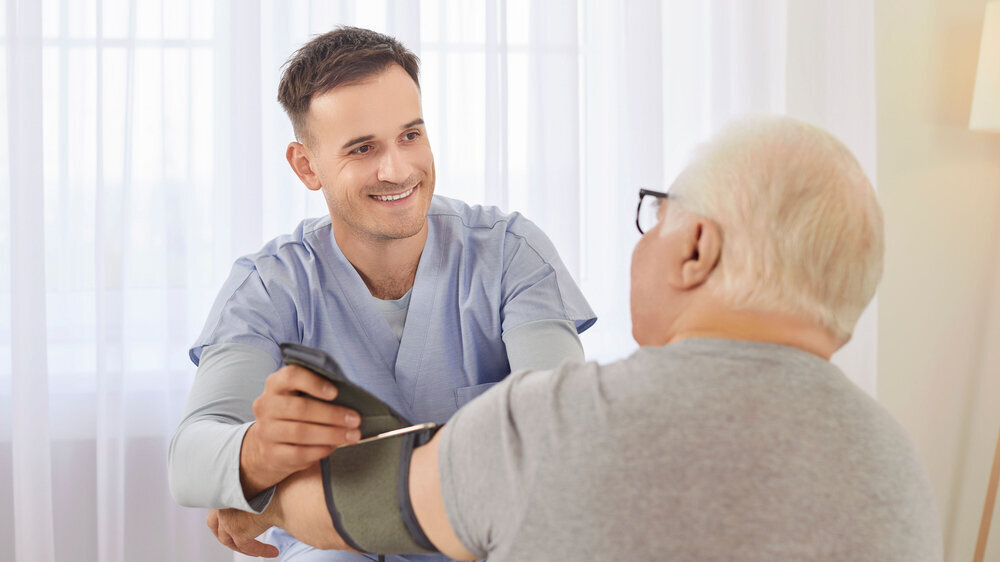 Nurse measure blood pressure of a sick senior mature male patient visiting him at home. Krankenpfleger