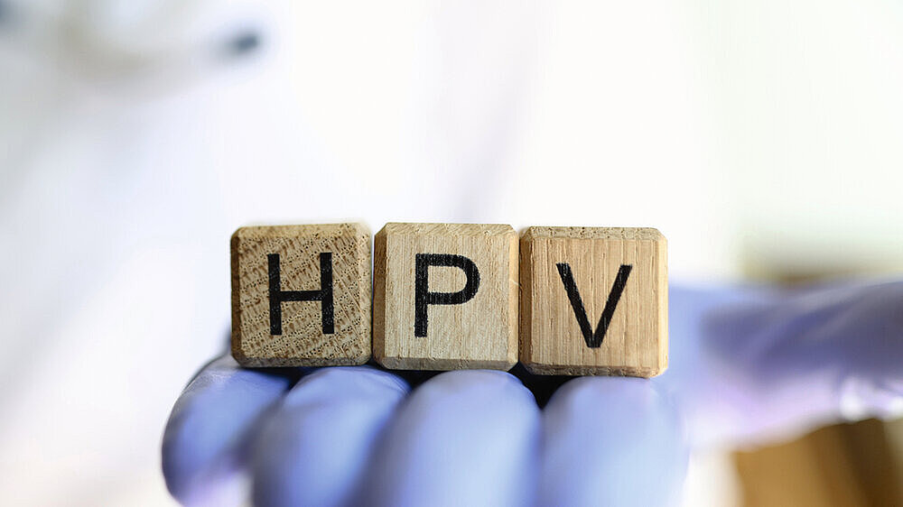 Close-up of female practitioner hand holding wooden cubes with word hpv. Medicine and human papillomavirus acronym concept