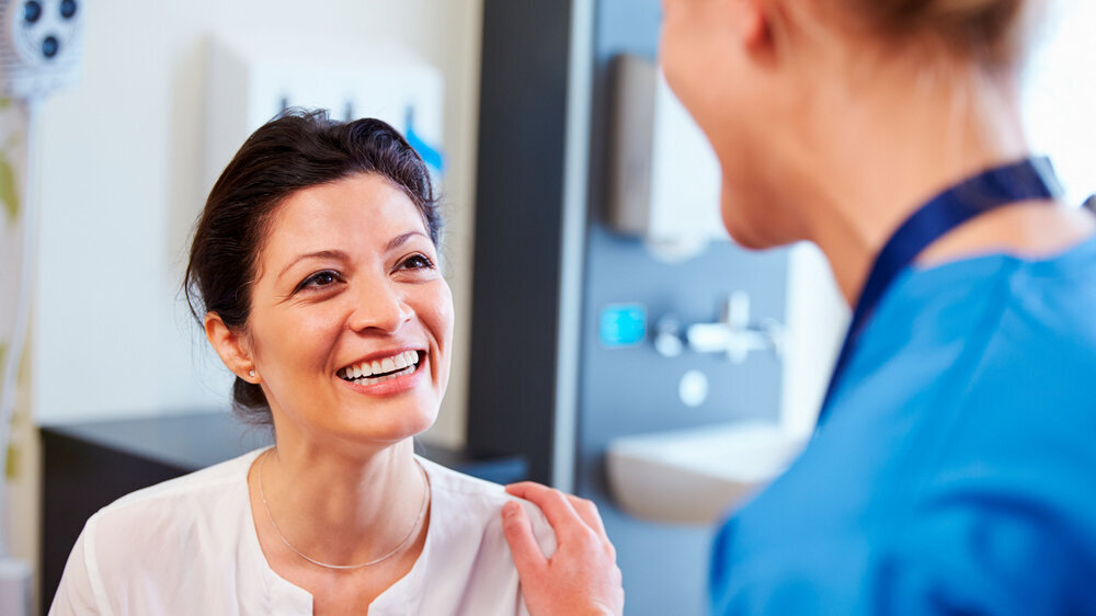 Female Patient Being Reassured By Doctor In Hospital Room Patientin mit Ärztin oder Krankenschwester