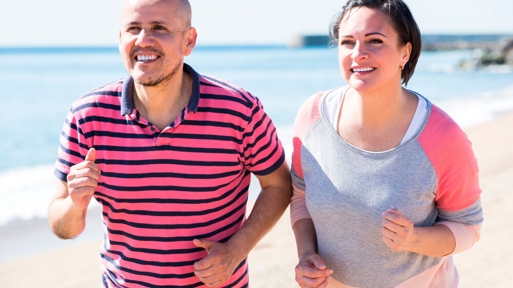 494470909 Smiling sportive mature couple jogging together at seaside