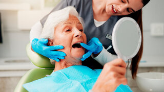 Zahnarzt, ältere Frau und Beratung mit Spiegel für Zahnreinigung, Zahnimplantat oder Mundhygiene.