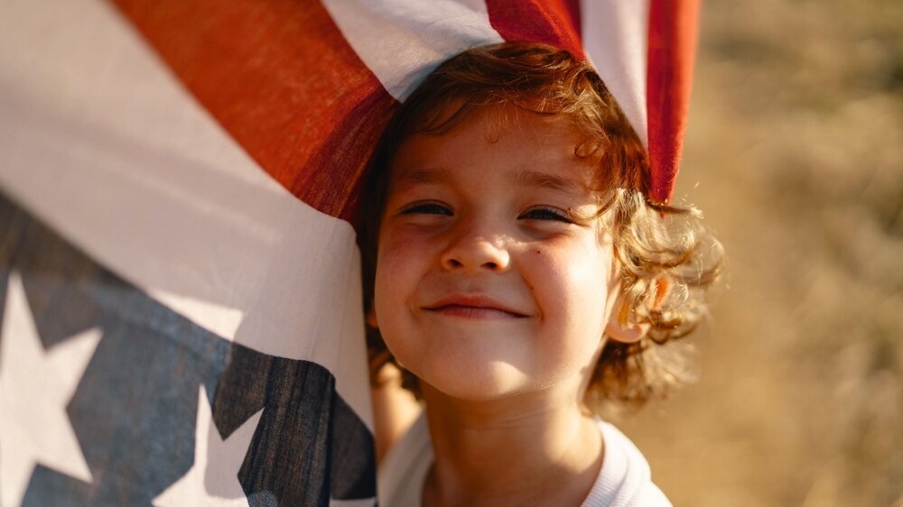 Happy little boy patriot running in the field with American flag Junge mit USA-Flagge
