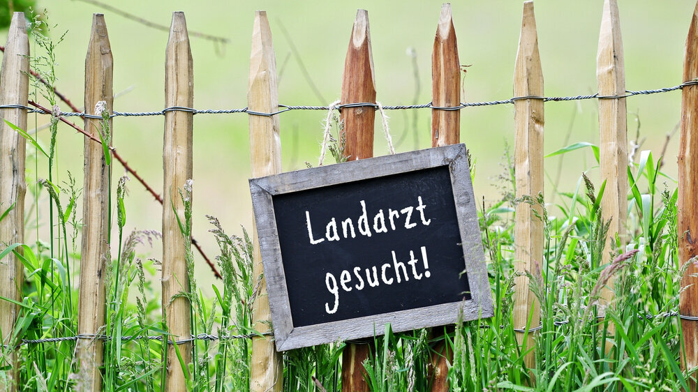 Schild hängt am Gartenzaun: Landarzt gesucht Schild hängt am Gartenzaun: Landarzt gesucht