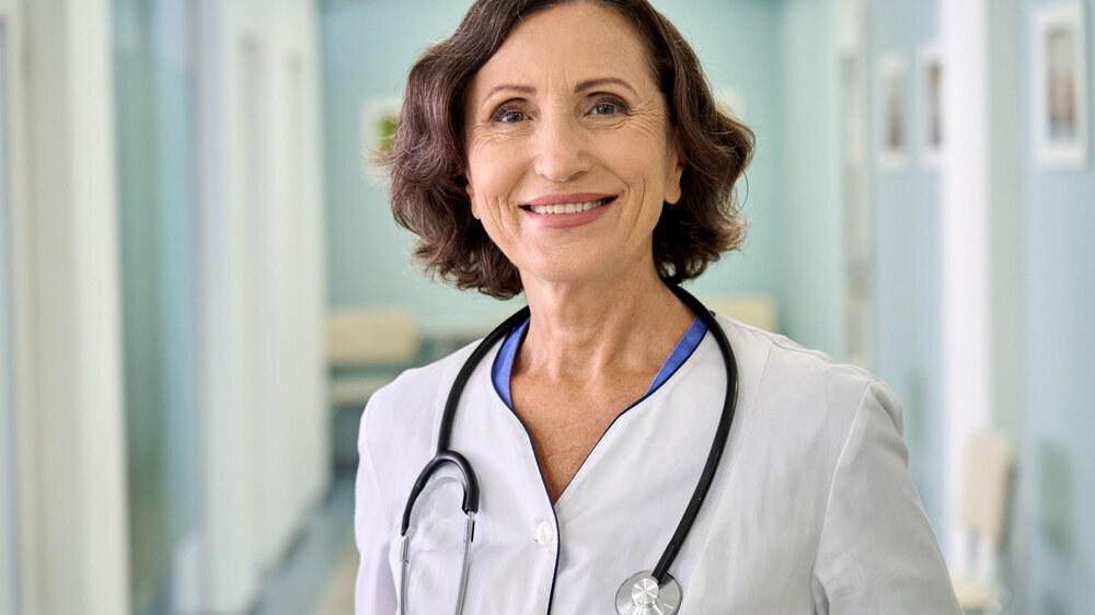 Smiling female happy doctor pediatrician standing in clinic hospital. Portrait. ältere Ärztin