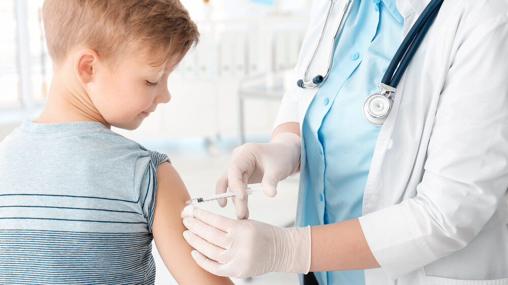 Arzt impft kleinen Jungen im Krankenhaus.