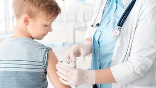 Arzt impft kleinen Jungen im Krankenhaus.