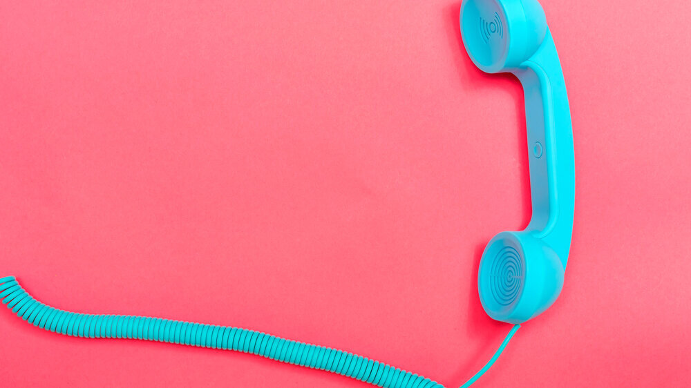 Telefon Blauer Telefonhörer im Retro-Design auf pinkem Hintergrund