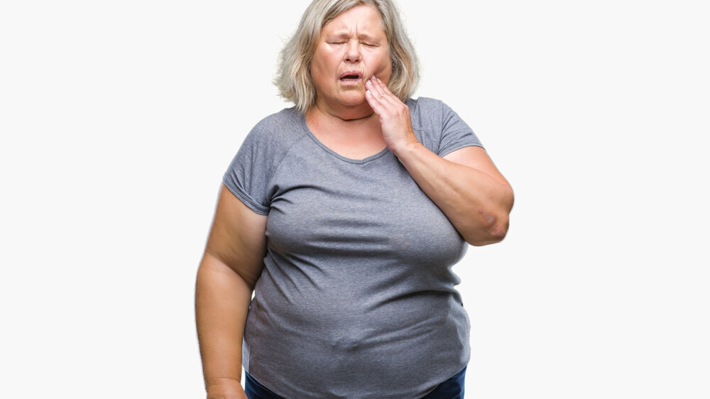 Senior plus size caucasian woman over isolated background touching mouth with hand with painful expression because of toothache or dental illness on teeth. Dentist concept.
