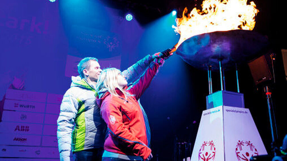 Die „Gesichter der Spiele“: Tanja Kirsch, Tobias Angerer und Stefan Birnbacher (verdeckt) entzünden das Special-Olympics-Feuer.