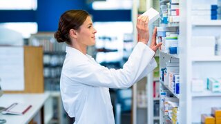 Apothekerin sucht Medikament aus dem Sortiment.