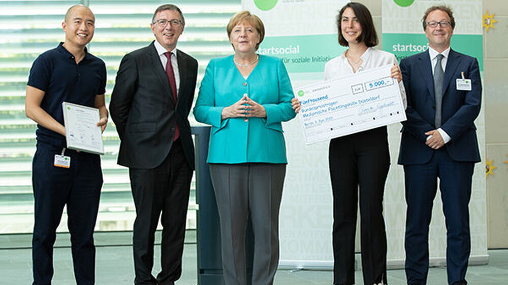 Dr. Dieter Düsedau, Gründer von startsocial e.V., Bundeskanzlerin Angela Merkel, Schirmherrin von startsocial e.V., und Dr. Tobias Wachinger, Senior Partner bei McKinsey & Company, gemeinsam mit den startsocial-Preisträgern Long Tang Chieu und Enid