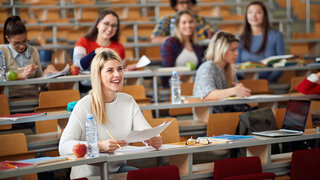 Smiling girl sitting in amphitheater with colleagues