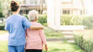 Pflegende mit Seniorin im Garten