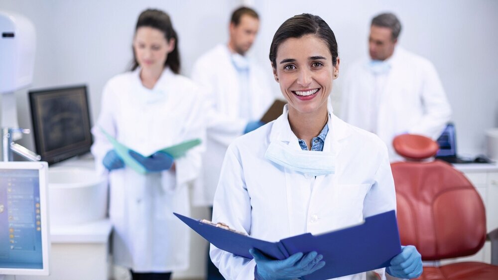 Smiling dentist holding file at dental clinic