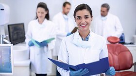 Smiling dentist holding file at dental clinic