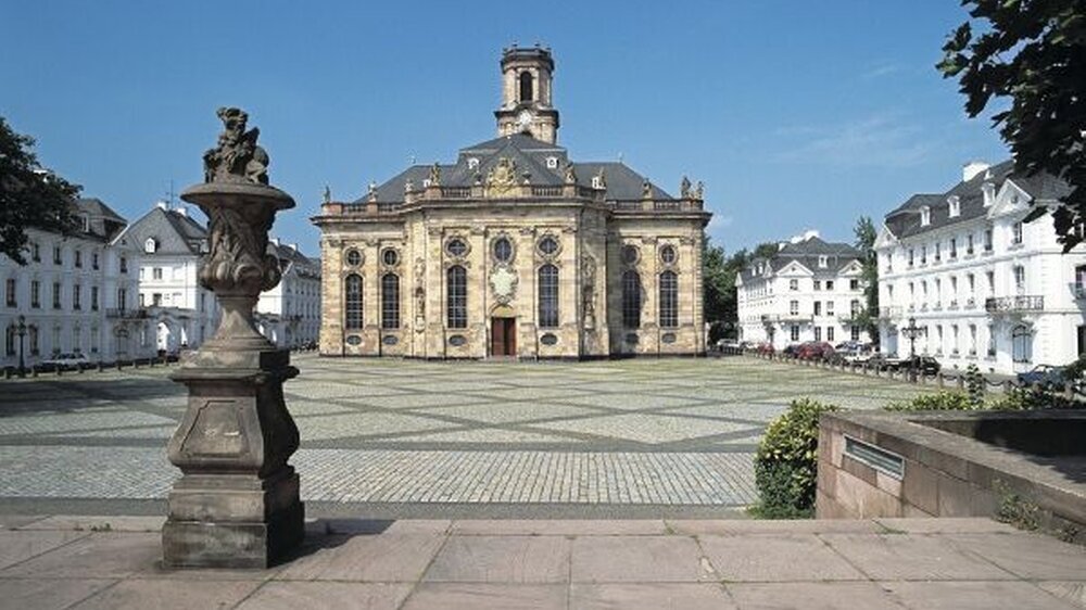 Saarbrücken (hier die Ludwigskirche) ist Veranstaltungsort des saarländischen Zahnärzte- Team-Tages. Unten: Festredner Wolfram Arnim Candidus (l.) mit Dr. Hans-Joachim Lellig.