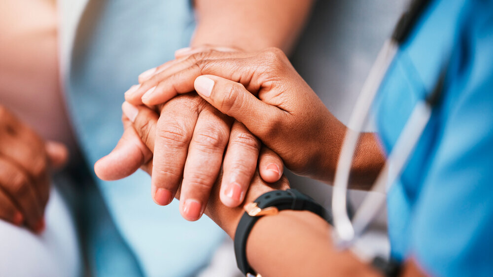 Pflegepersonal hält die Hand einer Patientin Pflegepersonal hält die Hand einer Patientin