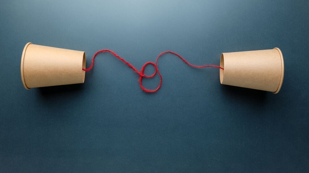 Brown cups phone with red string set on faded background, old style phone, two-way communication Zuhören im Gespräch