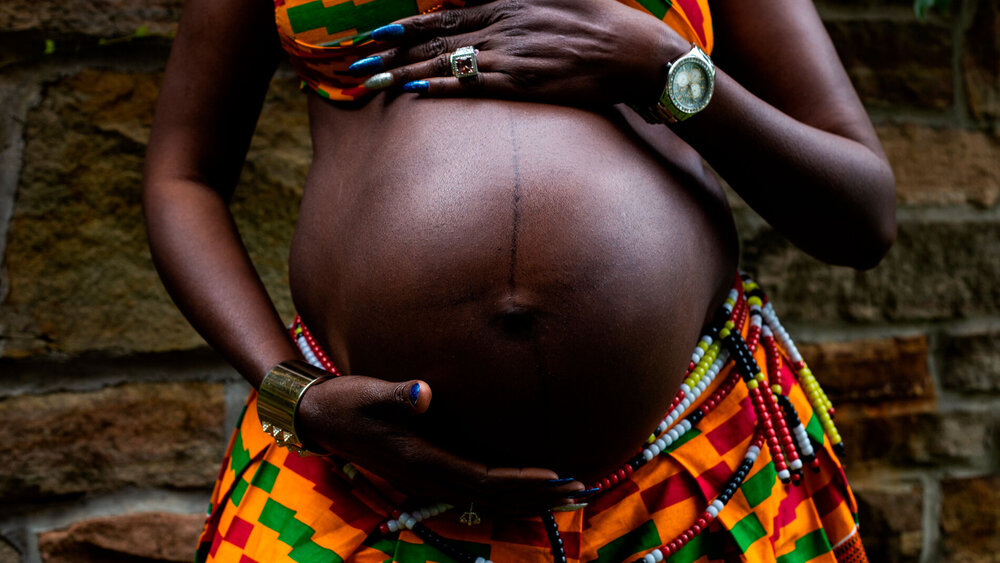 Schwangere Frau mit dunkler Hautfarbe zeigt ihren Bauch