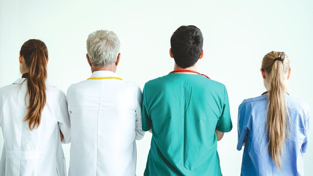 Praxisteam von hinten: Unterschiedliche Mitarbeiter - jung, alt, männlich, weiblich