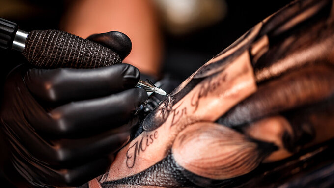 Ein Tattoo wird gestochen, Nadel trifft Haut. Ein Tattoo wird gestochen, Nadel trifft Haut.