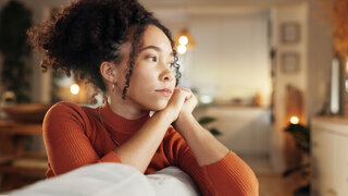 Depression, lonely and sad with face of woman on sofa in living room of home for contemplation. Bored, heartbreak and thinking with unhappy African person in apartment for breakup or separation.