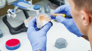 Ein Zahntechniker-Zahnarzt bei der Arbeit mit Prothesen in einem Labor mit Wachs auf einem Kiefermodell