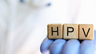 Close-up of female practitioner hand holding wooden cubes with word hpv. Medicine and human papillomavirus acronym concept