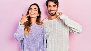 Young hispanic couple wearing casual clothes smiling cheerful showing and pointing with fingers teeth and mouth. dental health concept.