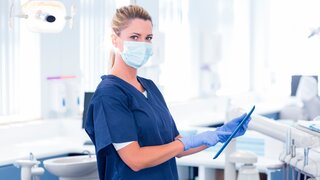 Zahnmedizinische Fachangestellte ZFA im Behandlungszimmer mit Tablet in der Hand.