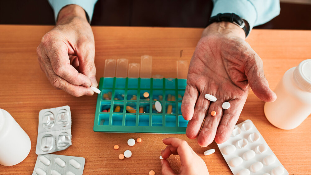 Älterer Mann, der seine Medikamente in einem Tablettenspender organisiert. Älterer Mann, der seine Medikamente in einem Tablettenspender organisiert.