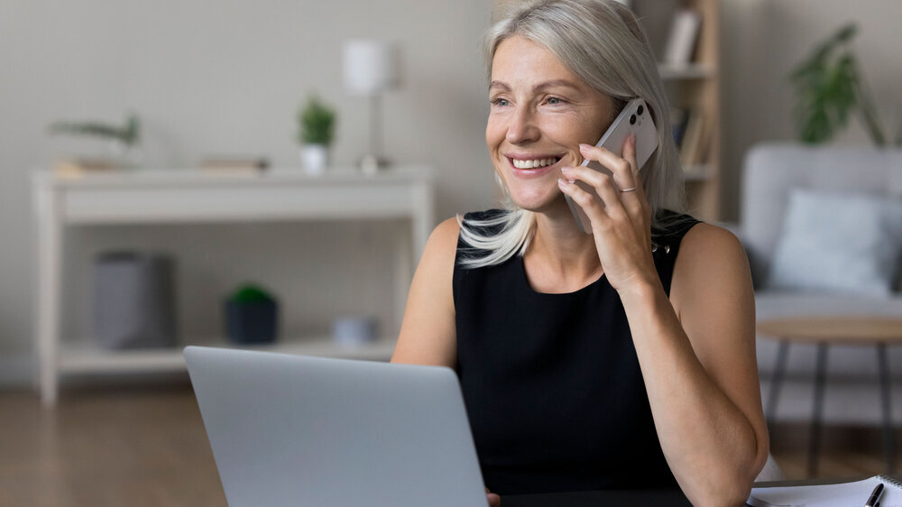 Frau am Laptop mit Smartphone