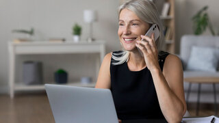 Frau am Laptop mit Smartphone