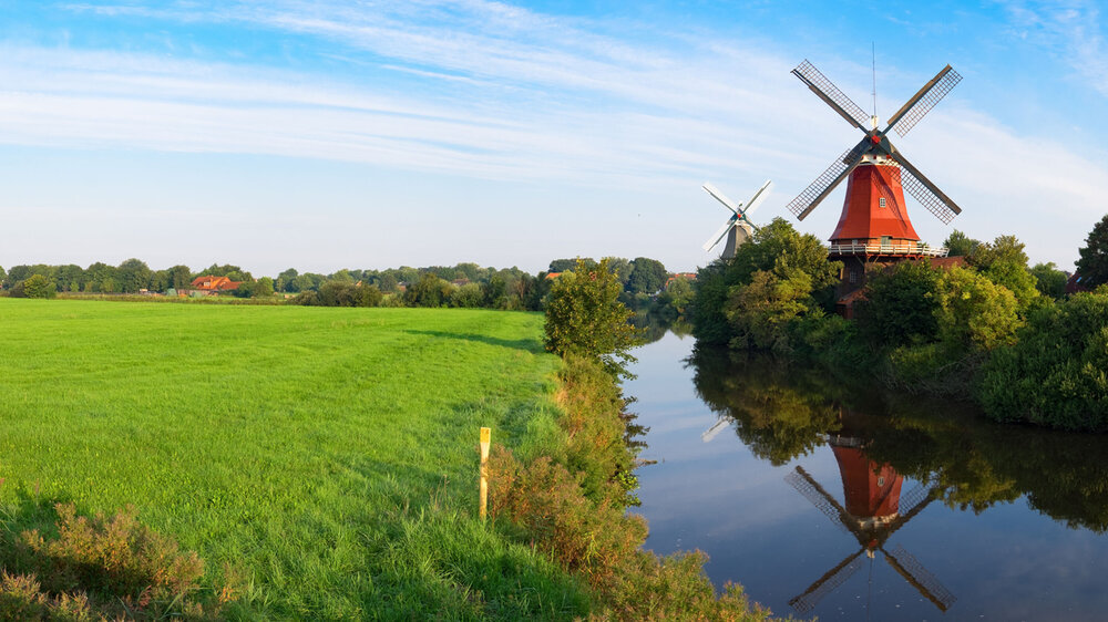 Zwillingswindmühlen von Greetsiel vor blaumen Himmel und grünen Wiesen, Niedersachsen. Zwillingswindmühlen von Greetsiel vor blaumen Himmel und grünen Wiesen, Niedersachsen.