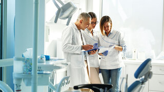 Medizinisches Zahnärzteteam in der Zahnarztpraxis bespricht die Praxis und prüft die Patientenliste.