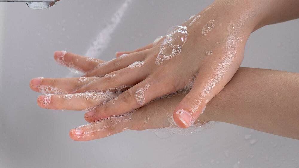 young girl soaped her hands and holds them under the tap in the bathroom young girl soaped her hands and holds them under the tap in the bathroom in the morning