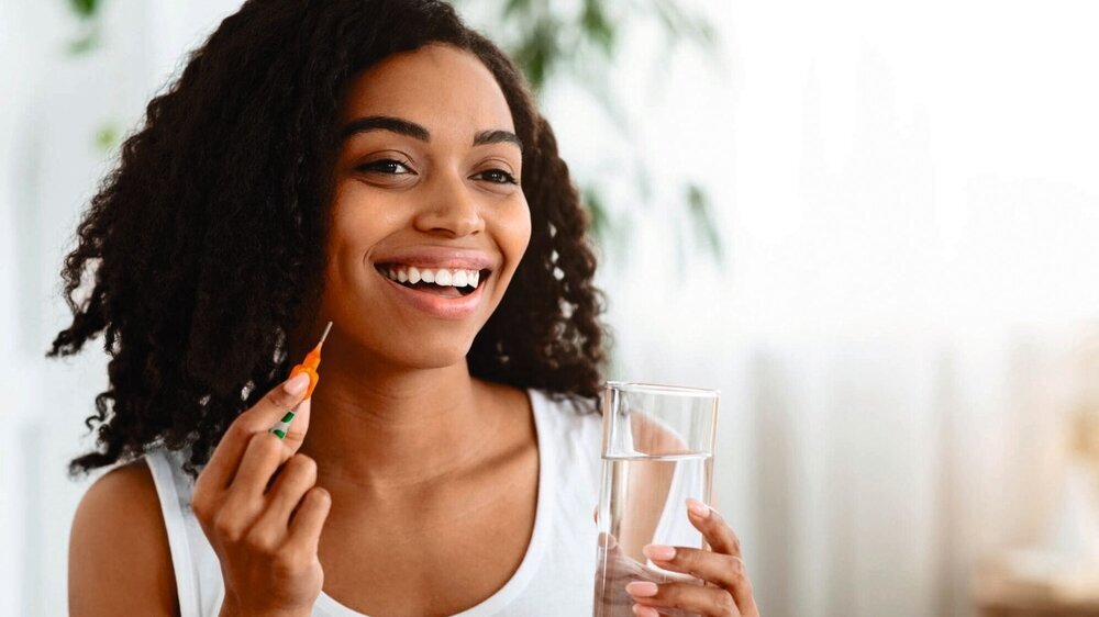 Healthy Diet Nutrition. Portrait Of Smiling Afro Woman Holding Vitamin Pill And Glass Of Mineral Water, Copy Space