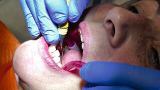 Woman in the 50s visit dentistry clinic for professional teeth treatment. Woman dentist bend over patient. Doctor holding instrument tool for oral cleaning. Professional toothache cure. Stomatology.