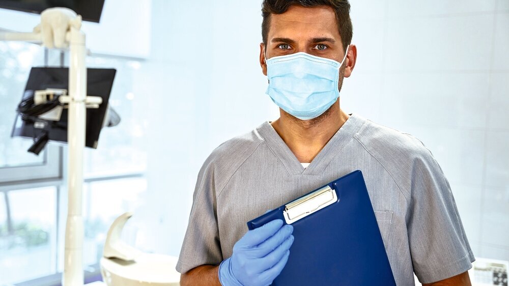 Attractive young dentist posing near dental chair Dokumentation Bürokratie Zahnarztpraxis