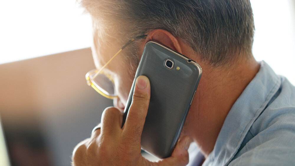 Nachaufnahme von einem Mann von der Seite mit Handy am Ohr. Nachaufnahme von einem Mann von der Seite mit Handy am Ohr.