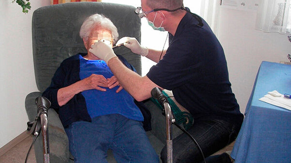 Die Patientin sitzt im Sessel: Geht man hier einfach in die Knie und stützt den eigenen Körper etwas über die Seitenlehne ab, ist nicht nur die Kommunikation auf Augenhöhe ein Gewinn, sondern bei Schwerhörigkeit zusätzlich der Mund näher am Ohr und