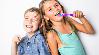 Schulkinder putzen sich die Zähne.