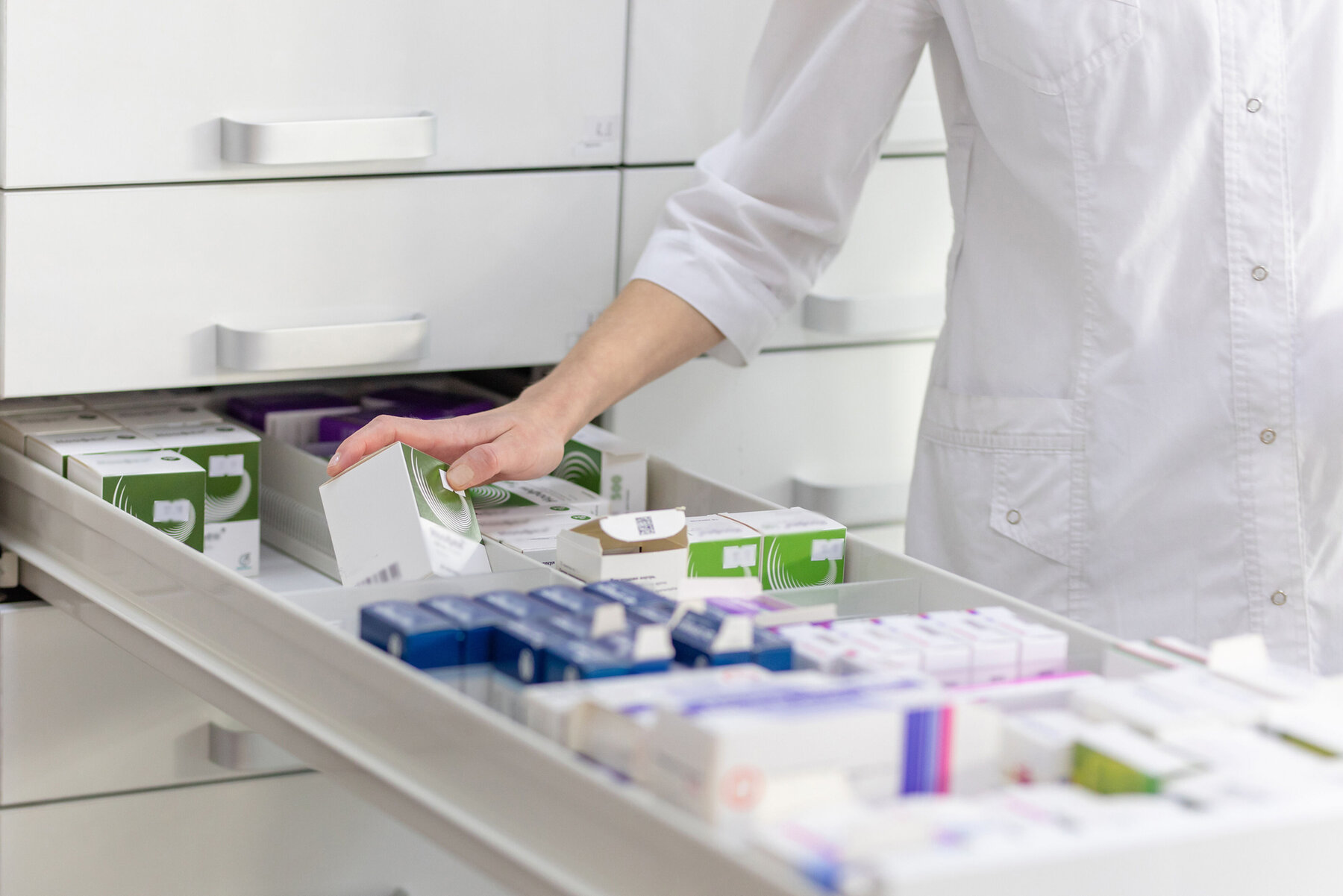 Apothekerin hält Medikamentenschachtel und Kapselpackung in einer Drogerie. Apothekerin hält Medikamentenschachtel und Kapselpackung in einer Drogerie.