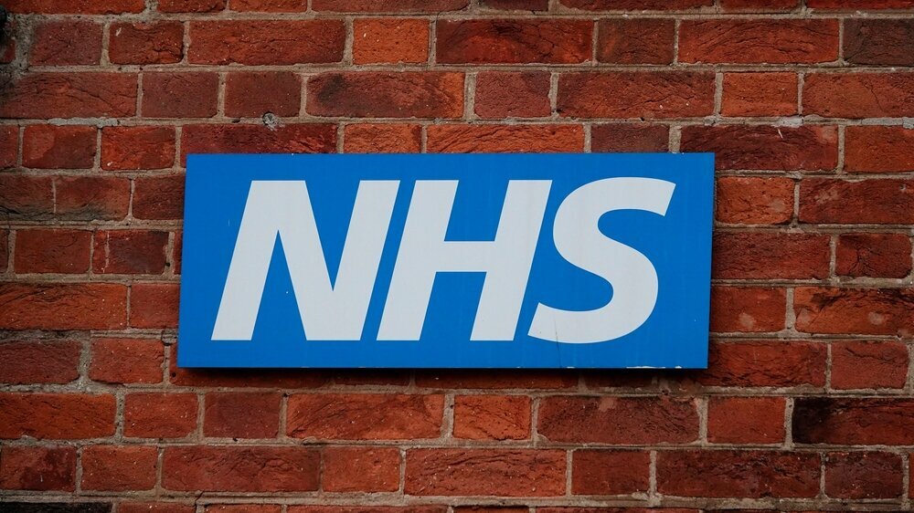 Blaues und weißes NHS-Zeichen an einer Backsteinmauer in York, Großbritannien.