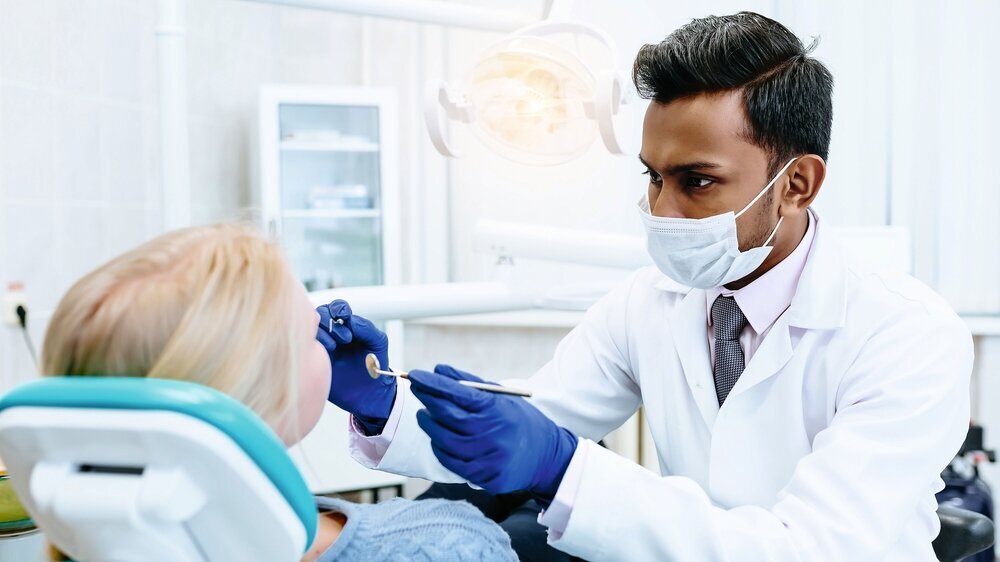 young confident asian male dentist Medical treatment to a female patient at the clinic. Dental clinic concept. Behandlung beim Zahnarzt