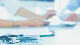 Attentive senior doctor listenint to patient in her office.