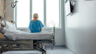 Älterne Patientin sitzt einsam auf ihrem Bett im Krankenhaus.