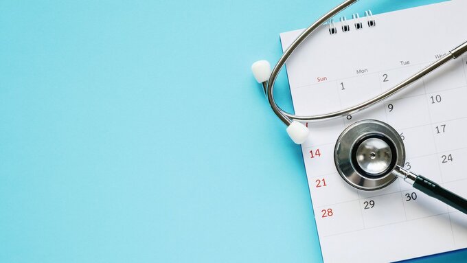 Stethoskop mit Kalenderblatt Datum auf blauem Hintergrund Arzttermin medizinisches Konzept.