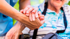 Nurse consoling senior woman holding her hand